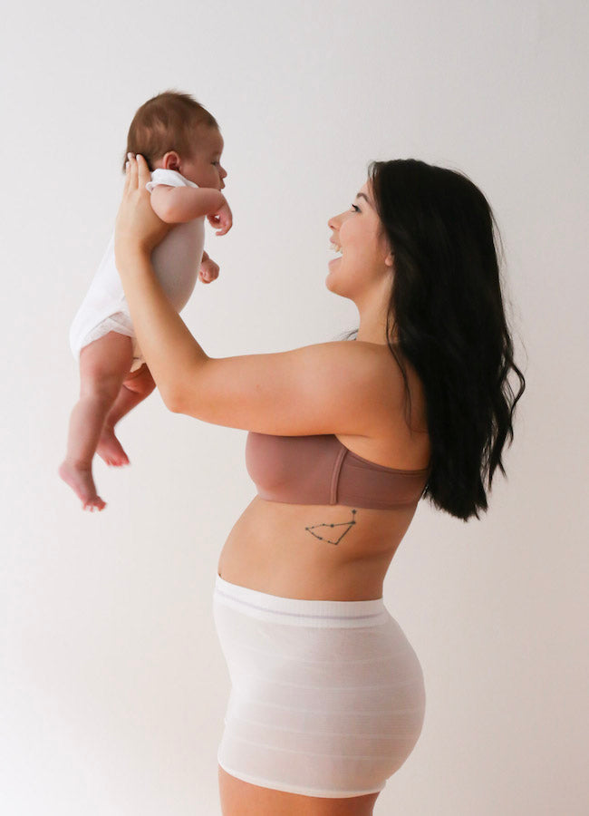 Mother wearing mesh underwear holding up baby